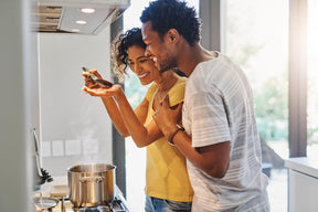 man and woman in kitchen tasting food